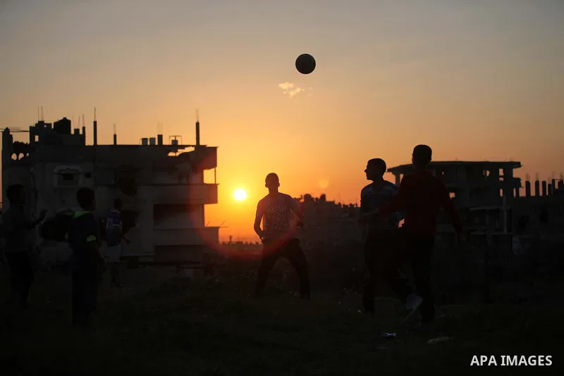 Palestinian youths play football in front of the rubbles of houses, which were destroyed during the recent Israeli offensive on Gaza Strip, in the last sunset of 2014, in Shijaiyah neighborhood, east Gaza city December 3...