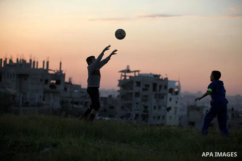 Palestinian youths play football in front of the rubbles of houses, which were destroyed during the recent Israeli offensive on Gaza Strip, in the last sunset of 2014, in Shijaiyah neighborhood, east Gaza city December 3...