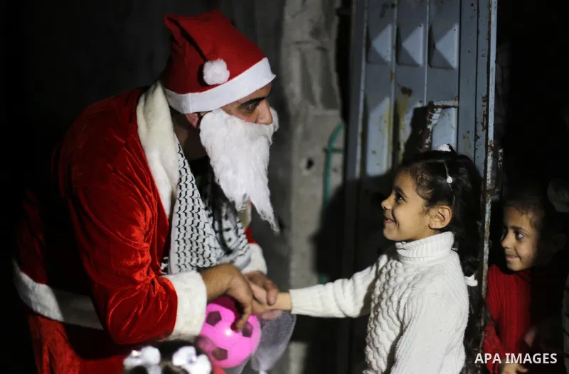 A Palestinian man in Santa Claus costume distributes gifts to children as part of Christmas and New Year festivities, in Shijaiyah neighborhood, east Gaza on December 31, 2014. Photo by Mohammed Asad