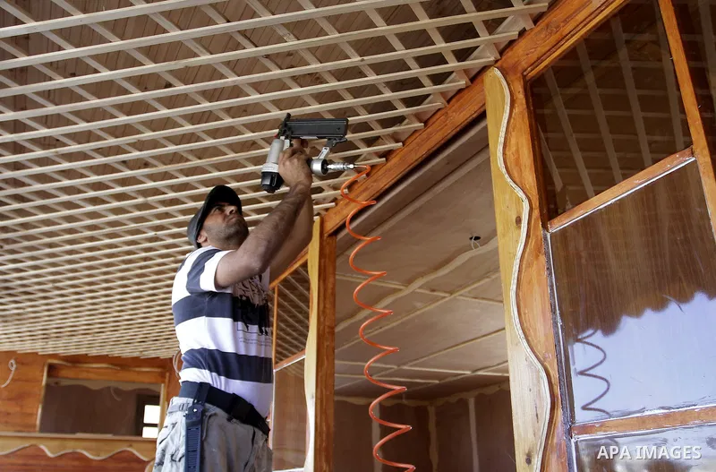 Palestinian carpenter Ibrahim Dokhan, 36, works using wood to rebuild a house, which was damaged during the recent Israeli offensive on Gaza Strip, in Rafah in the southern Gaza Strip, December 31, 2014. Because of the s...