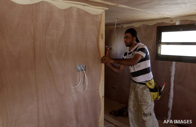 Palestinian carpenter Ibrahim Dokhan, 36, works using wood to rebuild a house, which was damaged during the recent Israeli offensive on Gaza Strip, in Rafah in the southern Gaza Strip, December 31, 2014. Because of the s...