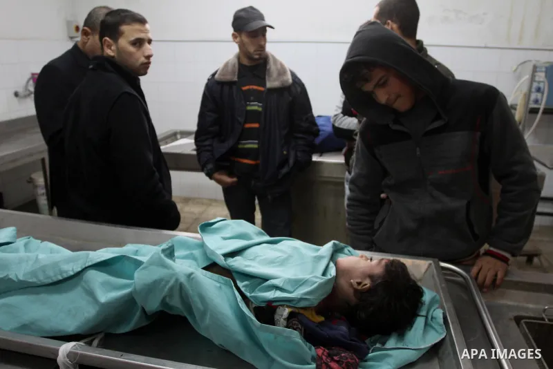 A Palestinian man stands next the body of one two boys of EL-Habeel family who were dead when fire broke out due to an electrical malfunction in the backup power system, in a hospital in Gaza City January 4, 2015. Palest...