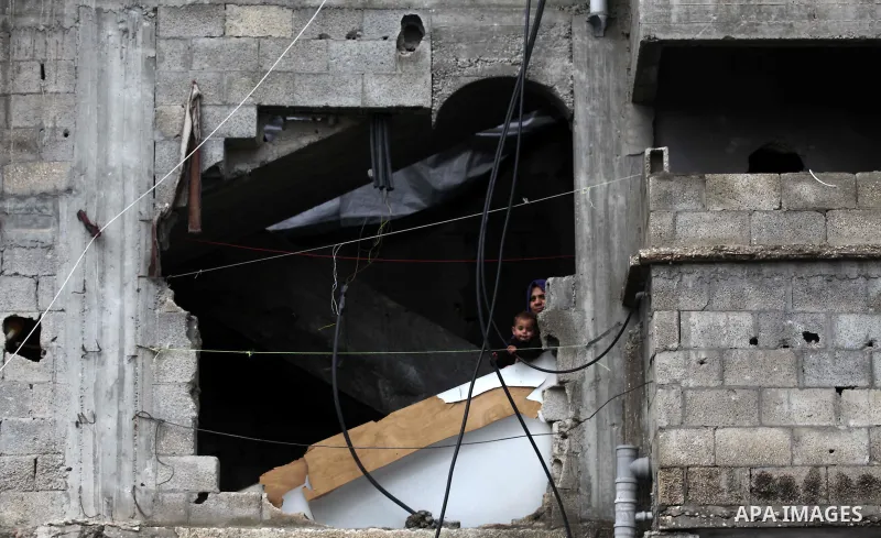 A Palestinian woman with her son look from a hole in her house which was destroyed during the 51-days Israeli offensive on Gaza Strip, in Shijaiyah neighborhood, east Gaza city January 4, 2015. Photo by Ashraf Amra
