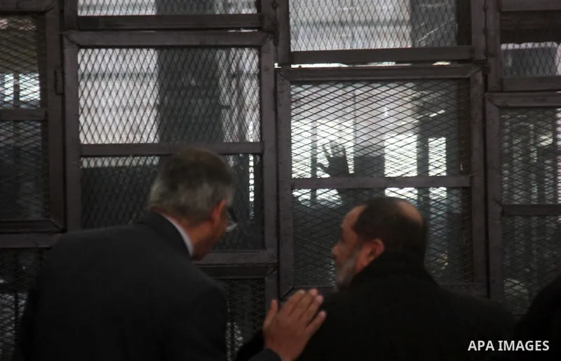 Egyptian suspects of the Muslim Brotherhood movement leaders stand behind a court room during their trial in Cairo on January 5, 2014. Cairo criminal court adjourned, today, Monday, the trial of supreme leader of Muslim...