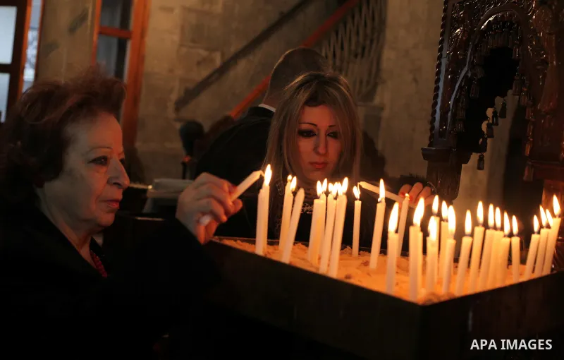 Palestinian Orthodox Christian women light a candle in a church during Christmas celebrations on January 7, 2015 in Gaza City. The Orthodox Church celebrates Christmas and other religious holidays according to the Julian...