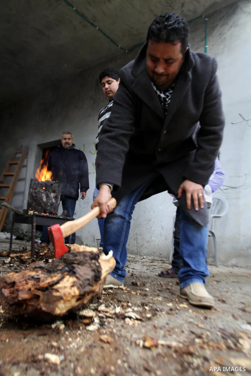 A Palestinian man cut the wood to warm others on fire during a heavy winter storm in the West Bank city of Nablus January 7, 2015. A storm buffeted the Middle East with blizzards, rain and strong winds on Wednesday, keep...