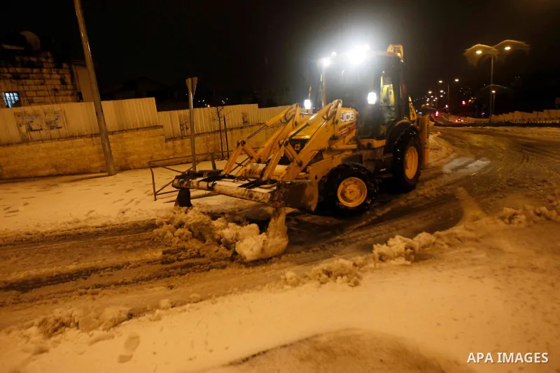 A bulldozer clears a road from snow in Jerusalem on January 7, 2015. As high winds battered the region and temperatures plummeted to zero, Israel police closed the two main access routes to Jerusalem several hours before...