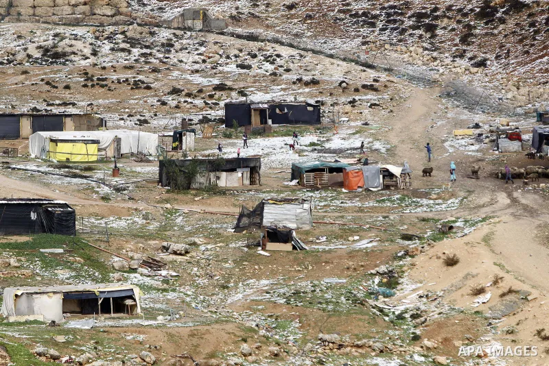 Palestinian Bedouins walk between their tents near the controversial Israeli barrier that runs along the Shuafat refugee camp after snowfall in the West Bank near Jerusalem January 8, 2015. A storm buffeted the Middle Ea...