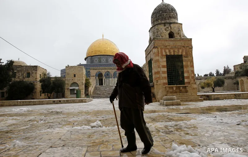 A man walks in front of the Dome of the Rock on the compound known to Muslims as Noble Sanctuary in Jerusalem's Old City after snowfall January 8, 2015. A storm buffeted the Middle East with blizzards, rain and strong wi...