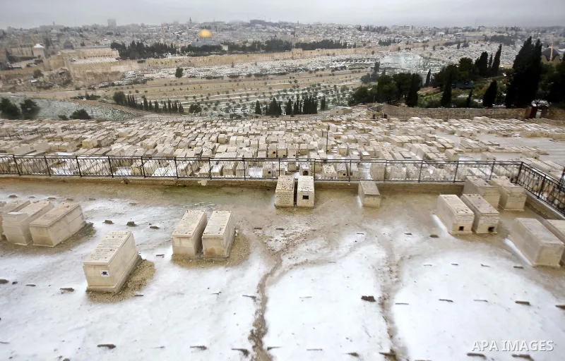 The Dome of the Rock is seen in the background as snow covers the Mount of Olives cemetery outside Jerusalem's Old City after snowfall January 8, 2015. A storm buffeted the Middle East with blizzards, rain and strong win...