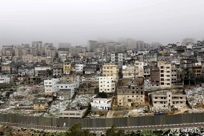 Snowfall is seen around a section of the controversial Israeli barrier that runs along the Shuafat refugee camp in the West Bank near Jerusalem January 8, 2015. A storm buffeted the Middle East with blizzards, rain and s...