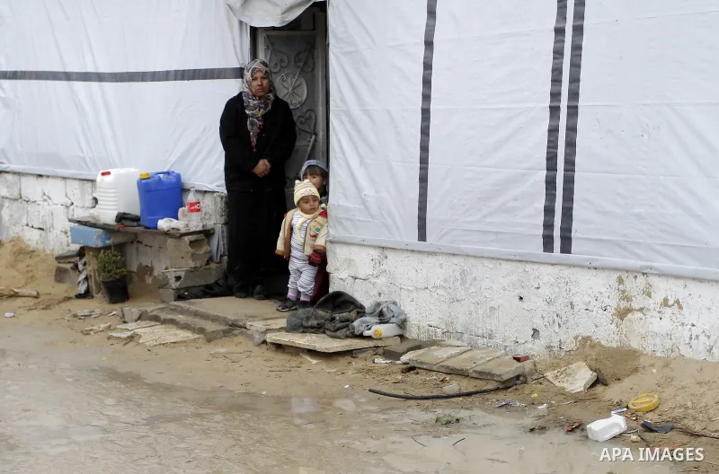A Palestinian woman, who lives in a container as a temporary replacement for her house which was destroyed by what she said was Israeli shelling during a 50- day-war last summer, stands outside a container on a stormy da...
