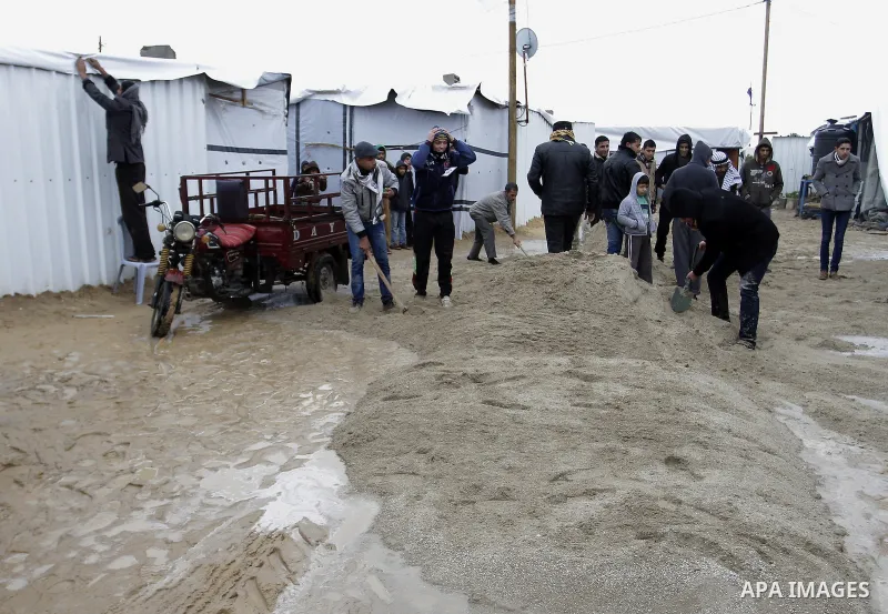 Palestinians, whose houses were destroyed by what they said was Israeli shelling during a 50- day-war last summer, work outside their containers on a stormy day in the east of Khan Younis in the southern Gaza Strip Janua...