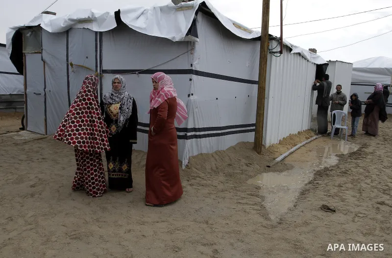 Palestinians, whose houses were destroyed by what they said was Israeli shelling during a 50- day-war last summer, stand outside containers used as temporary replacement for their damaged homes, on a stormy day in the ea...
