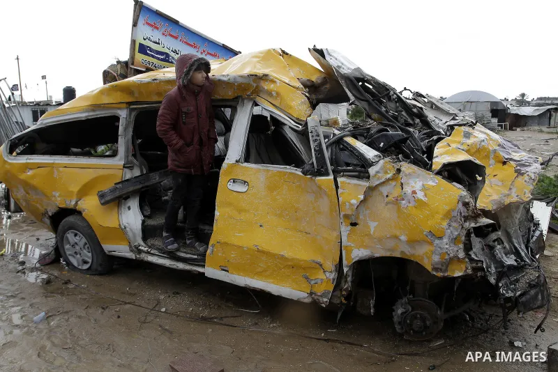 A Palestinian boy, who lives in a container as a temporary replacement for his family's house which was destroyed by what she said was Israeli shelling during a 50- day-war last summer, plays on the remains of a car on a...