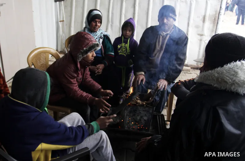 Palestinians, whose houses were destroyed by what they said was Israeli shelling during a 50- day-war last summer, warm themselves around a fire on a stormy day in the east of Khan Younis in the southern Gaza Strip Janua...