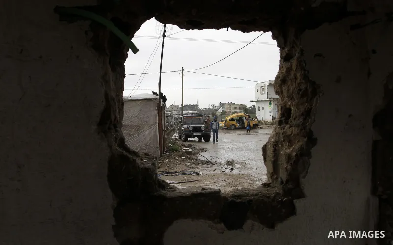 Palestinians, whose houses were destroyed by what they said was Israeli shelling during a 50- day-war last summer, stand outside containers used as temporary replacement for their damaged homes, on a stormy day in the ea...