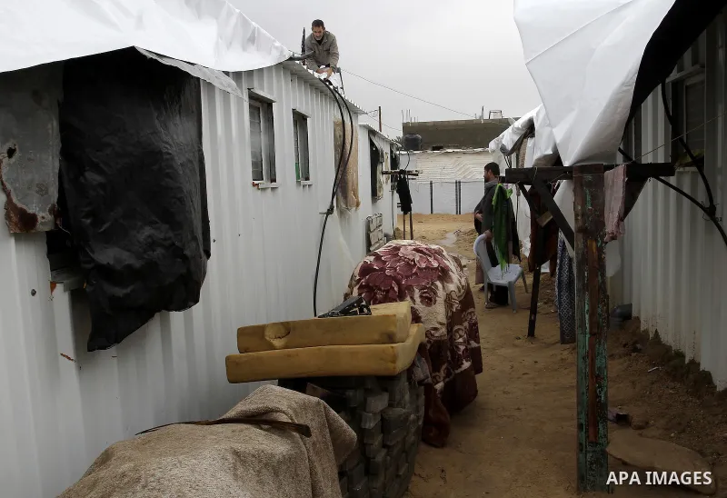 Palestinians, whose houses were destroyed by what they said was Israeli shelling during a 50- day-war last summer, work outside their containers on a stormy day in the east of Khan Younis in the southern Gaza Strip Janua...