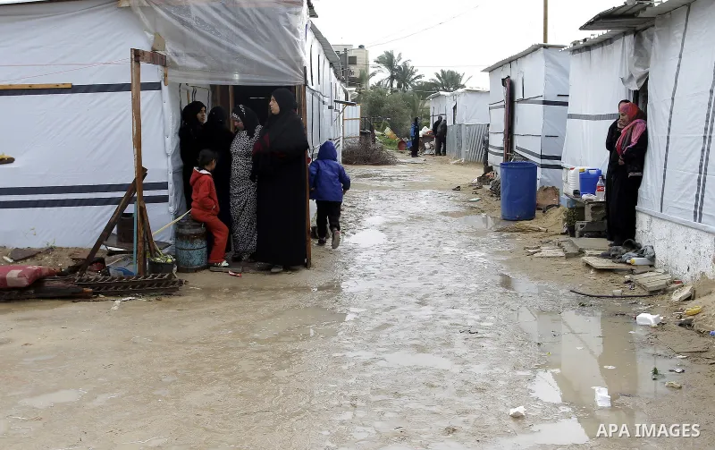 Palestinians, whose houses were destroyed by what they said was Israeli shelling during a 50- day-war last summer, stand outside containers used as temporary replacement for their damaged homes, on a stormy day in the ea...