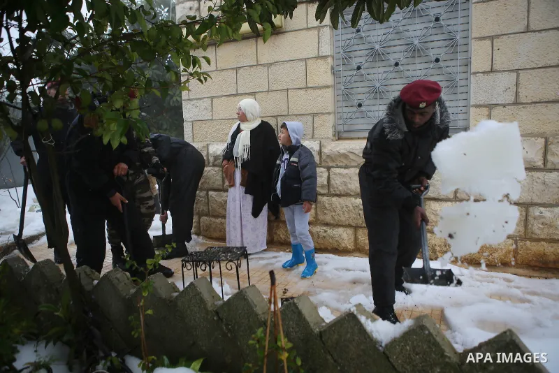 Palestinian security forces remove the snow from a street after a snowfall in the West Bank city of Ramallah, January 8, 2015. A storm buffeted the Middle East with blizzards, rain and strong winds on Wednesday, keeping...