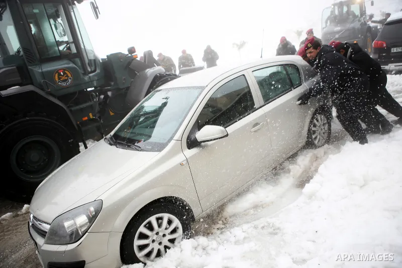 Palestinian security forces push a car after a snowfall in the West Bank city of Ramallah, January 8, 2015. A storm buffeted the Middle East with blizzards, rain and strong winds on Wednesday, keeping people at home acro...