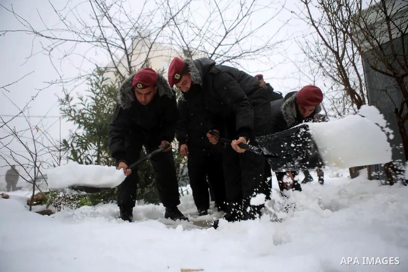 Palestinian security forces remove the snow from a street after a snowfall in the West Bank city of Ramallah, January 8, 2015. A storm buffeted the Middle East with blizzards, rain and strong winds on Wednesday, keeping...