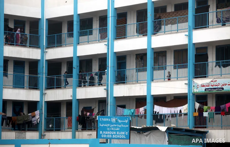 Palestinians walk outside classrooms at a United Nations (UN) run school sheltering Palestinians, whose houses were destroyed in the 50- day-war Israeli last summer, during a winter storm in Beit Hanoun in the northern G...