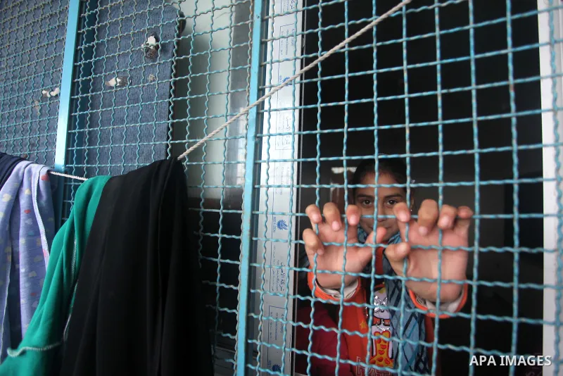 A Palestinian girl looks on from a classroom window at a United Nations (UN) run school sheltering Palestinians, whose houses were destroyed in the 50- day-war Israeli last summer, during a winter storm in Beit Hanoun in...