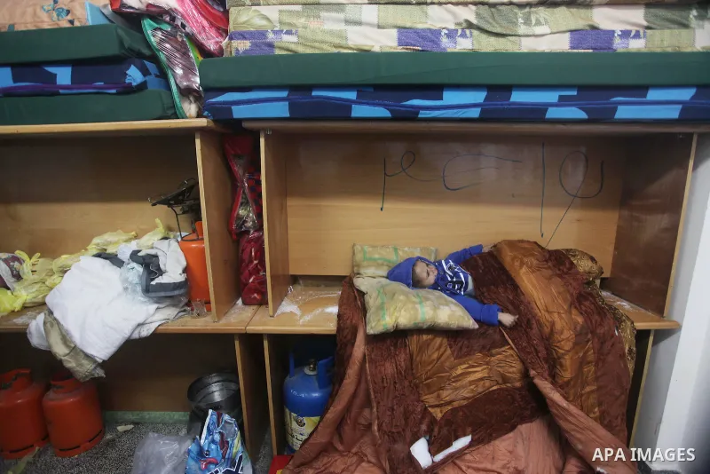 A Palestinian boy sleeps in a classroom at a United Nations (UN) run school sheltering Palestinians, whose houses were destroyed in the 50- day-war Israeli last summer, during a winter storm in Beit Hanoun in the norther...