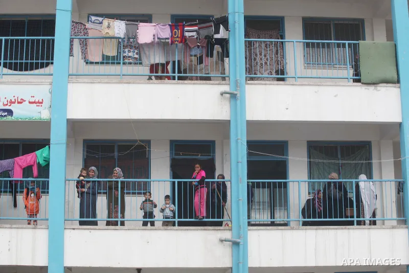 Palestinians stand outside classrooms at a United Nations (UN) run school sheltering Palestinians, whose houses were destroyed in the 50- day-war Israeli last summer, during a winter storm in Beit Hanoun in the northern...