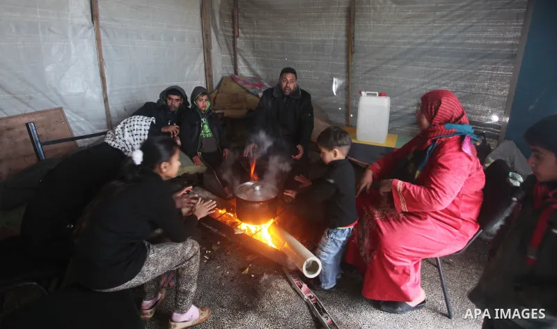 Palestinians warm themselves around a fire at a United Nations (UN) run school sheltering Palestinians, whose houses were destroyed in the 50- day-war Israeli last summer, during a winter storm in Beit Hanoun in the nort...