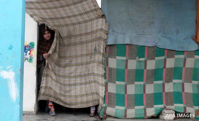 A Palestinian girl looks on behind a curtain at a United Nations (UN) run school sheltering Palestinians, whose houses were destroyed in the 50- day-war Israeli last summer, during a winter storm in Beit Hanoun in the no...