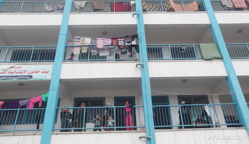 Palestinians stand outside classrooms at a United Nations (UN) run school sheltering Palestinians, whose houses were destroyed in the 50- day-war Israeli last summer, during a winter storm in Beit Hanoun in the northern...