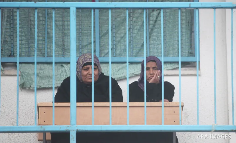 Palestinian women sit outside classrooms at a United Nations (UN) run school sheltering Palestinians, whose houses were destroyed in the 50- day-war Israeli last summer, during a winter storm in Beit Hanoun in the northe...