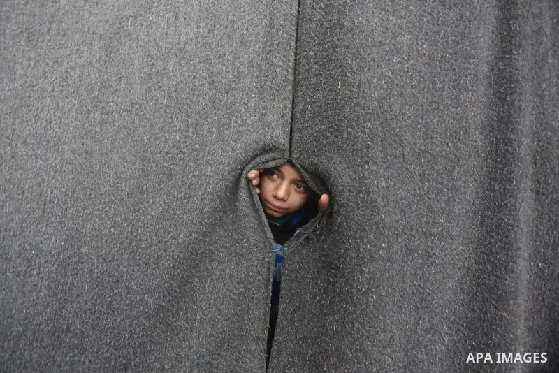 A Palestinian girl looks on behind a curtain at a United Nations (UN) run school sheltering Palestinians, whose houses were destroyed in the 50- day-war Israeli last summer, during a winter storm in Beit Hanoun in the no...
