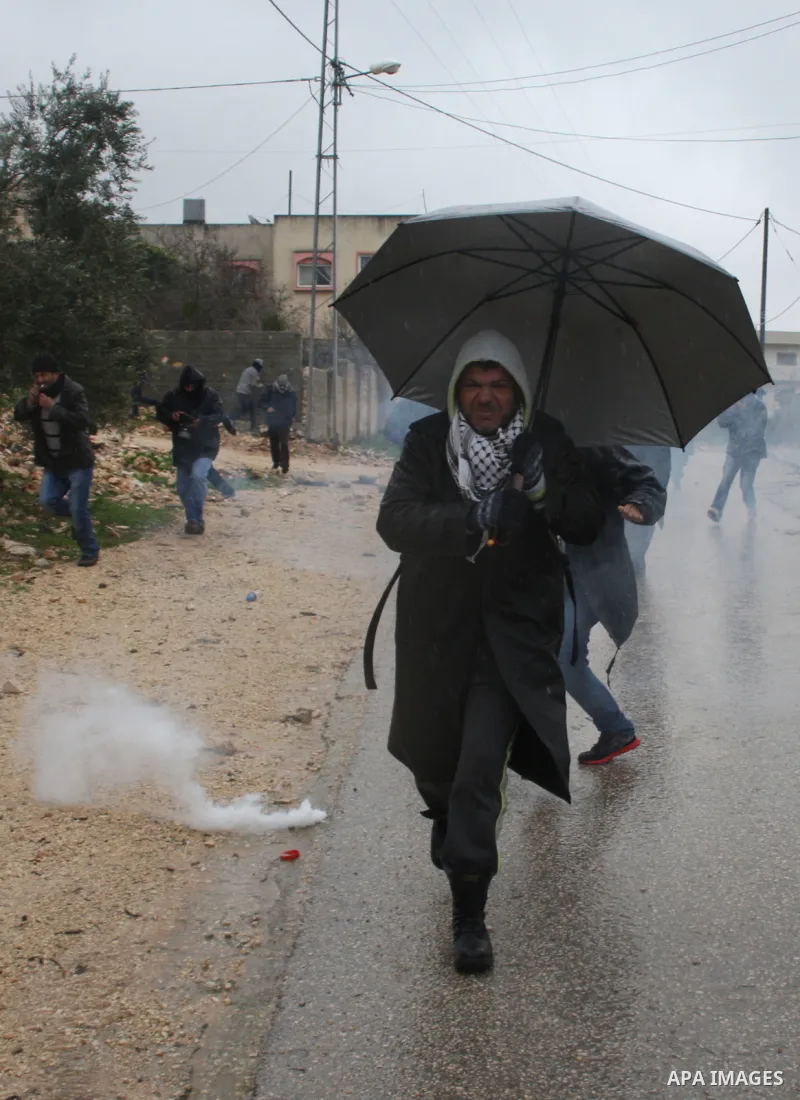 Palestinian protesters run from tear gas fired by Israeli security forces during clashes following a demonstration against the expropriation of Palestinian land by Israel in the West Bank village of Kfar Qaddum, near Nab...
