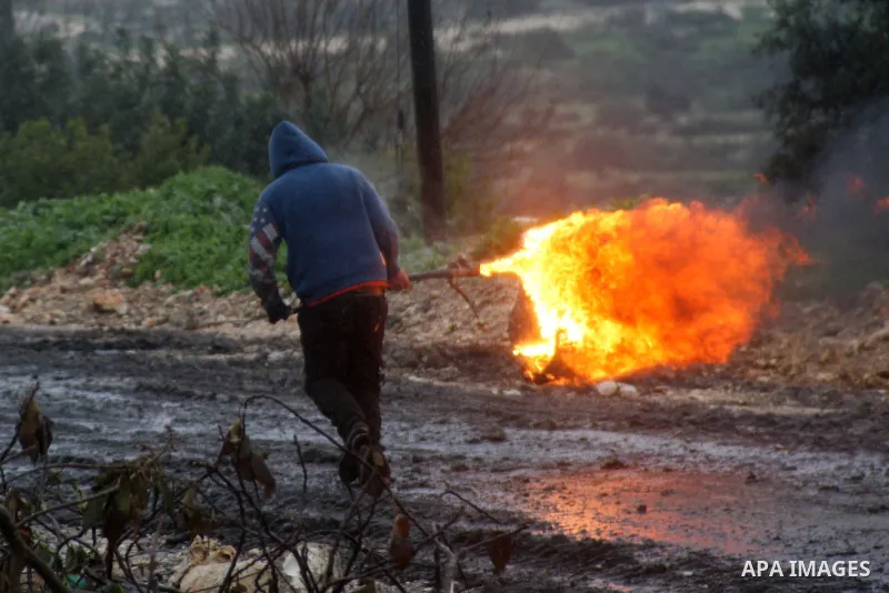 A Palestinian protester carries a burning tire during clashes with Israeli security forces following a demonstration against the expropriation of Palestinian land by Israel in the West Bank village of Kfar Qaddum, near N...