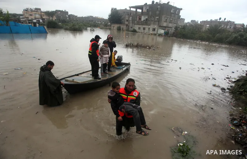 A members of Palestinian Civil Defence evacuates a boy following heavy rain that flooded their houses in Rafah in the southern Gaza Strip January 9, 2015. Heavy rains and near-freezing temperatures in the approaching sto...