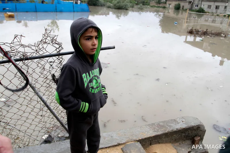 A Palestinian boy stands outside his family's house following heavy rain in Rafah in the southern Gaza Strip January 9, 2015. Heavy rains and near-freezing temperatures in the approaching storm threatened to deepen the m...