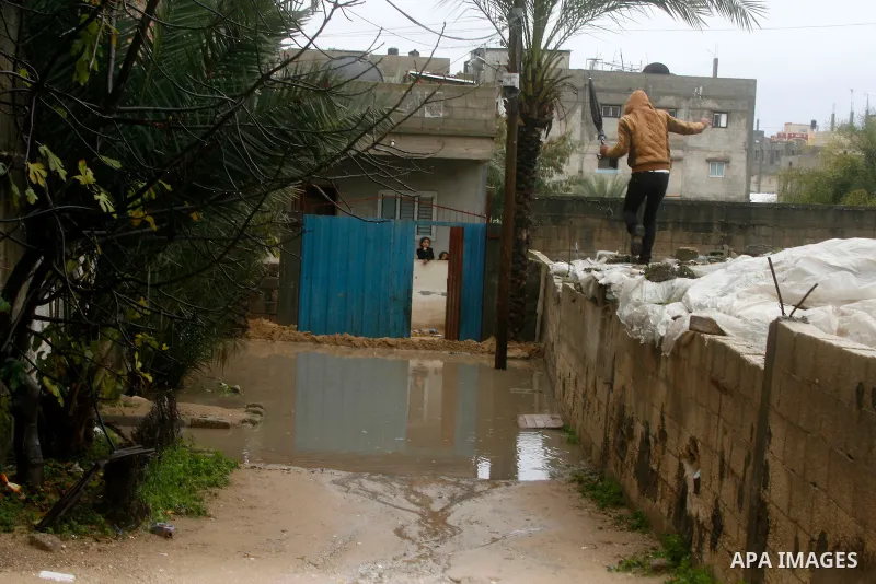 Palestinians look on as members of Civil Defence ride a boat as they evacuate people following heavy rain that flooded their houses in Rafah in the southern Gaza Strip January 9, 2015. Heavy rains and near-freezing tempe...