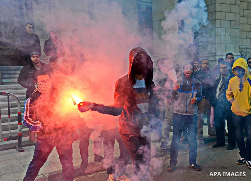 An Egyptian student who support ousted President Mohamed Morsi and the Muslim Brotherhood lights up a flare as they protest marking the first anniversary of the storming of Cairo University by Egyptian security forces, a...