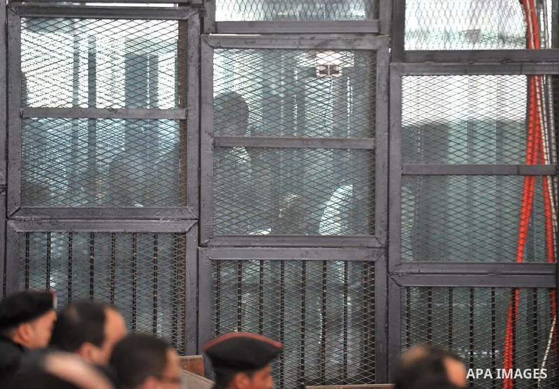 Defendants are seen behind bars during the retrial of Alaa Abdel Fattah and 24 others, in the courtroom in Cairo on January 15, 2015. The defendants were sentenced in June to 15 years in prison for holding an unlicensed...