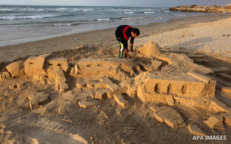 A Palestinian man creates a sand sculpture of a destroyed mosque at the beach of Gaza city, January 15, 2015 in protest against insulting of the prophet Mohammed. Issued first issue of French satirical weekly Charlie Heb...