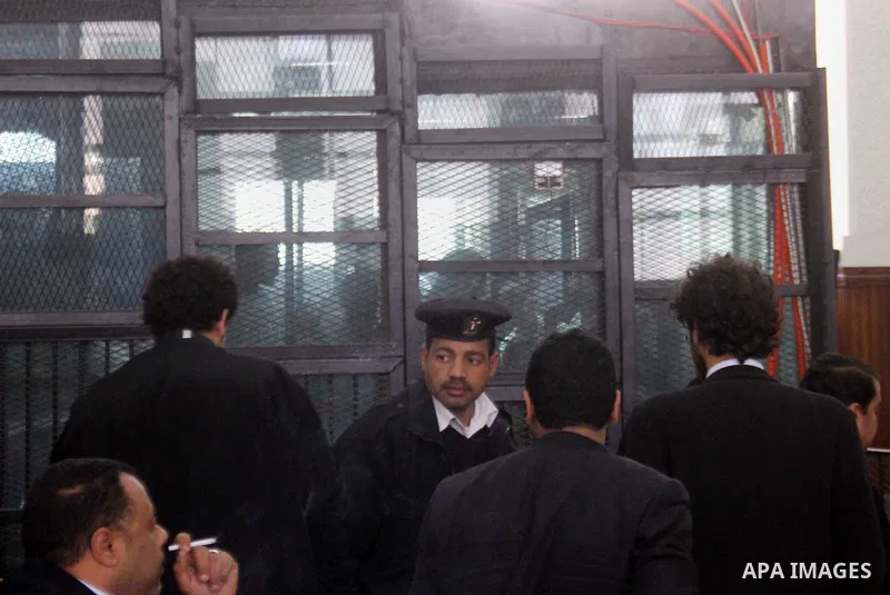 Defendants are seen behind bars during the retrial of Alaa Abdel Fattah and 24 others, in the courtroom in Cairo on January 17, 2015. The defendants were sentenced in June to 15 years in prison for holding an unlicensed...
