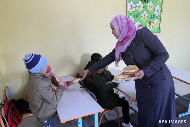 A Palestinian woman distributes sandwiches for deaf Palestinian children in a foundation for rehabilitation deaf children, in Khan Younis in the southern Gaza Strip, January 18, 2015. There are approximately 25,000 deaf...