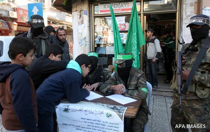 Palestinian members of Ezzedin al-Qassam brigades, the armed wing of Hamas movement, sit in a street to register young Palestinians for a winter military-style camp, in Gaza city on January 18, 2015. Hamas recently forme...