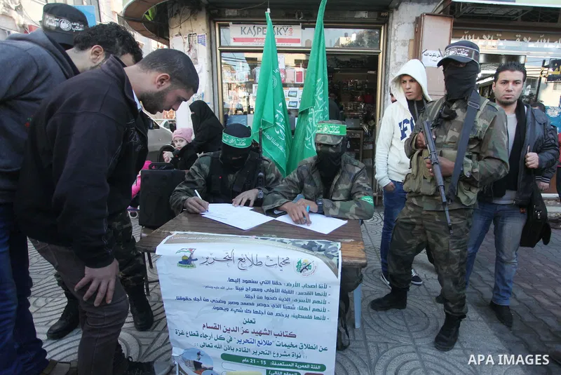 Palestinian members of Ezzedin al-Qassam brigades, the armed wing of Hamas movement, sit in a street to register young Palestinians for a winter military-style camp, in Gaza city on January 18, 2015. Hamas recently forme...