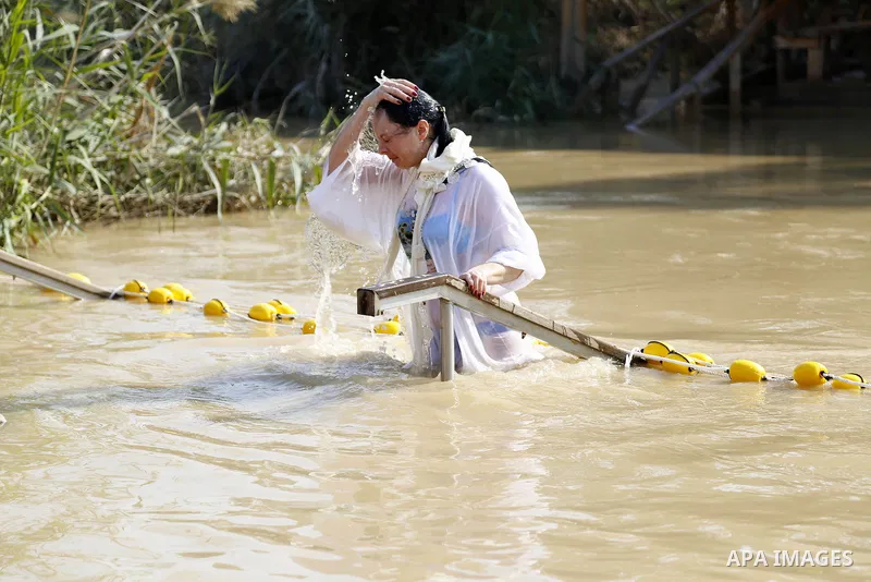 A Christian pilgrim dips in the water after a ceremony at the baptismal site known as Qasr el-Yahud on the banks of the Jordan River near the West Bank city of Jericho January 18, 2015. Orthodox Christians flocked to the...