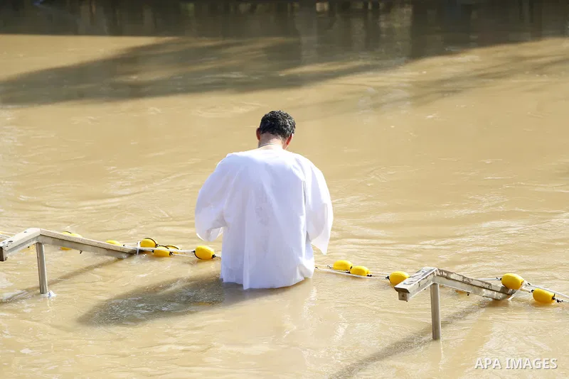 A Christian pilgrim dips in the water after a ceremony at the baptismal site known as Qasr el-Yahud on the banks of the Jordan River near the West Bank city of Jericho January 18, 2015. Orthodox Christians flocked to the...