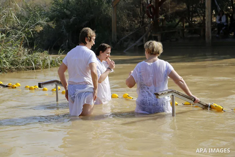 Christian pilgrims dip in the water after a ceremony at the baptismal site known as Qasr el-Yahud on the banks of the Jordan River near the West Bank city of Jericho January 18, 2015. Orthodox Christians flocked to the J...